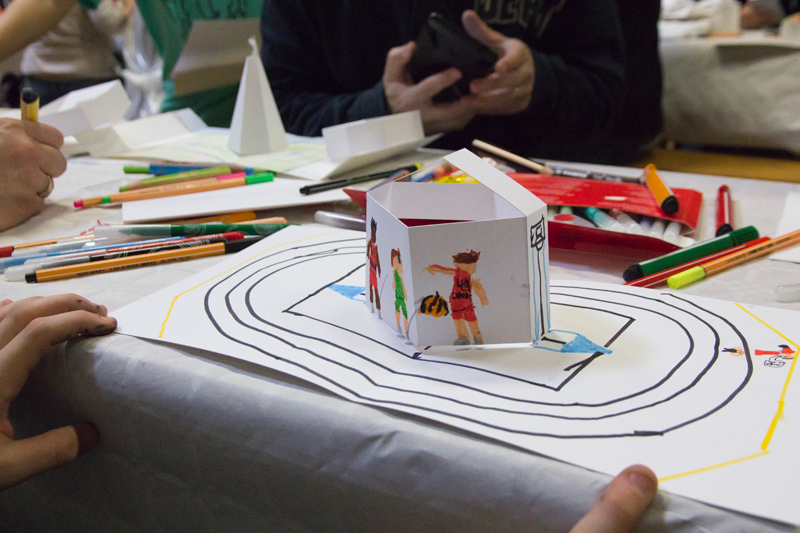 Un jeune participant a dessiné des sportifs et une piste de course autour du pop-up en papier.