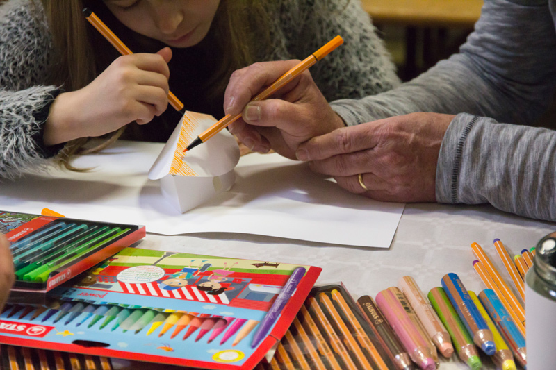 Une fille et son grand-père personnalisent la même maison en papier.