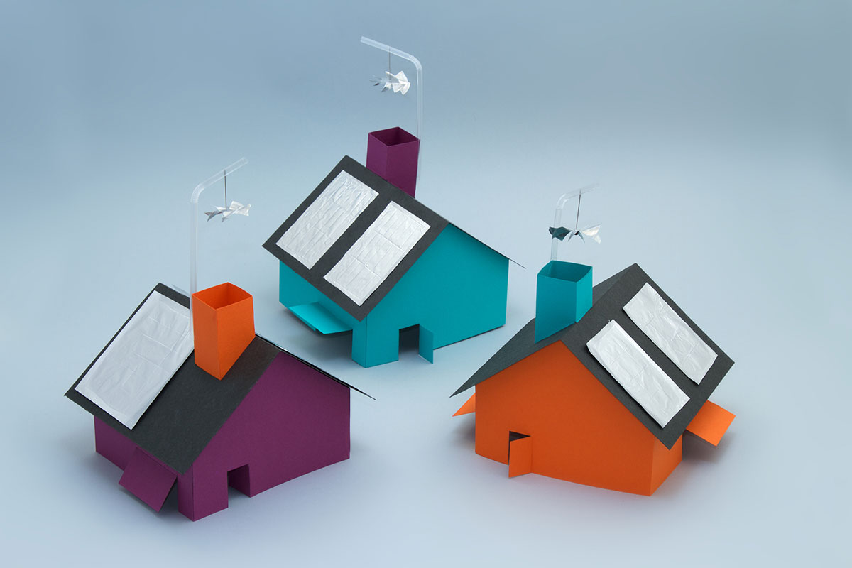 Trois maisons en papier coloré sont décorées de panneaux solaires en aluminium. Des hélices sont placées au dessus des cheminées. Elles tournent lorsque la maison est placée au soleil.